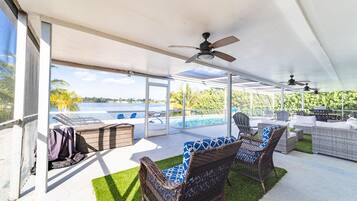 Une terrasse extérieure aménagée avec des meubles en osier, une piscine et une vue sur un lac.