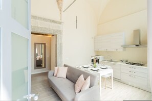 Eine moderne Küche mit weißen Schränken, einem Gasherd und einem Essbereich mit Tisch und Stühlen.