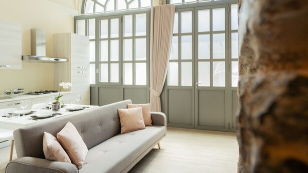 A modern kitchen with a dining area, a sofa, and large windows with curtains. - Romantic Escape in the 400s (Como)