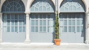 A building facade with three arched windows and a potted plant in the foreground. - Romantic Escape in the 400s (Como)