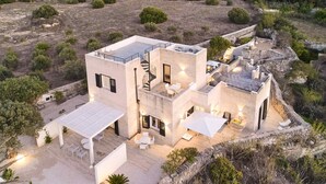 Uma villa moderna com telhado plano, área de estar ao ar livre e um muro de arrimo de pedra.