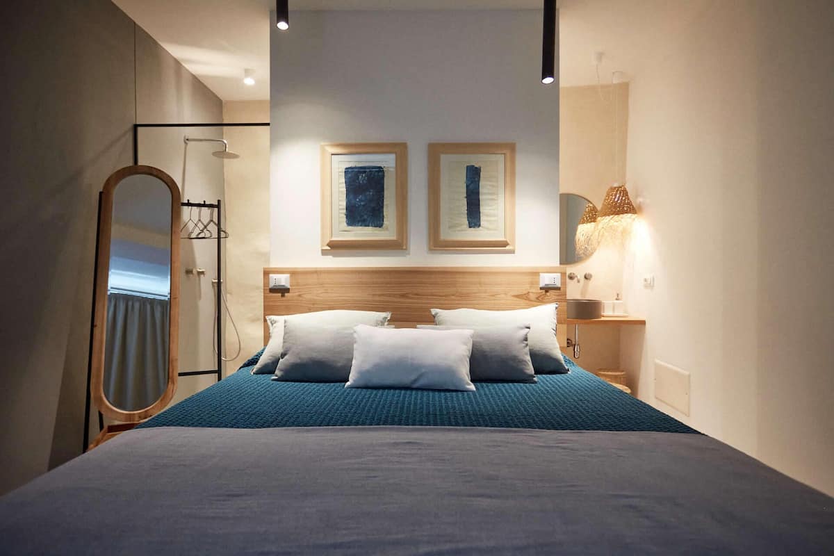 A modern hotel room with a large bed, a wooden headboard, and two framed abstract paintings on the wall.