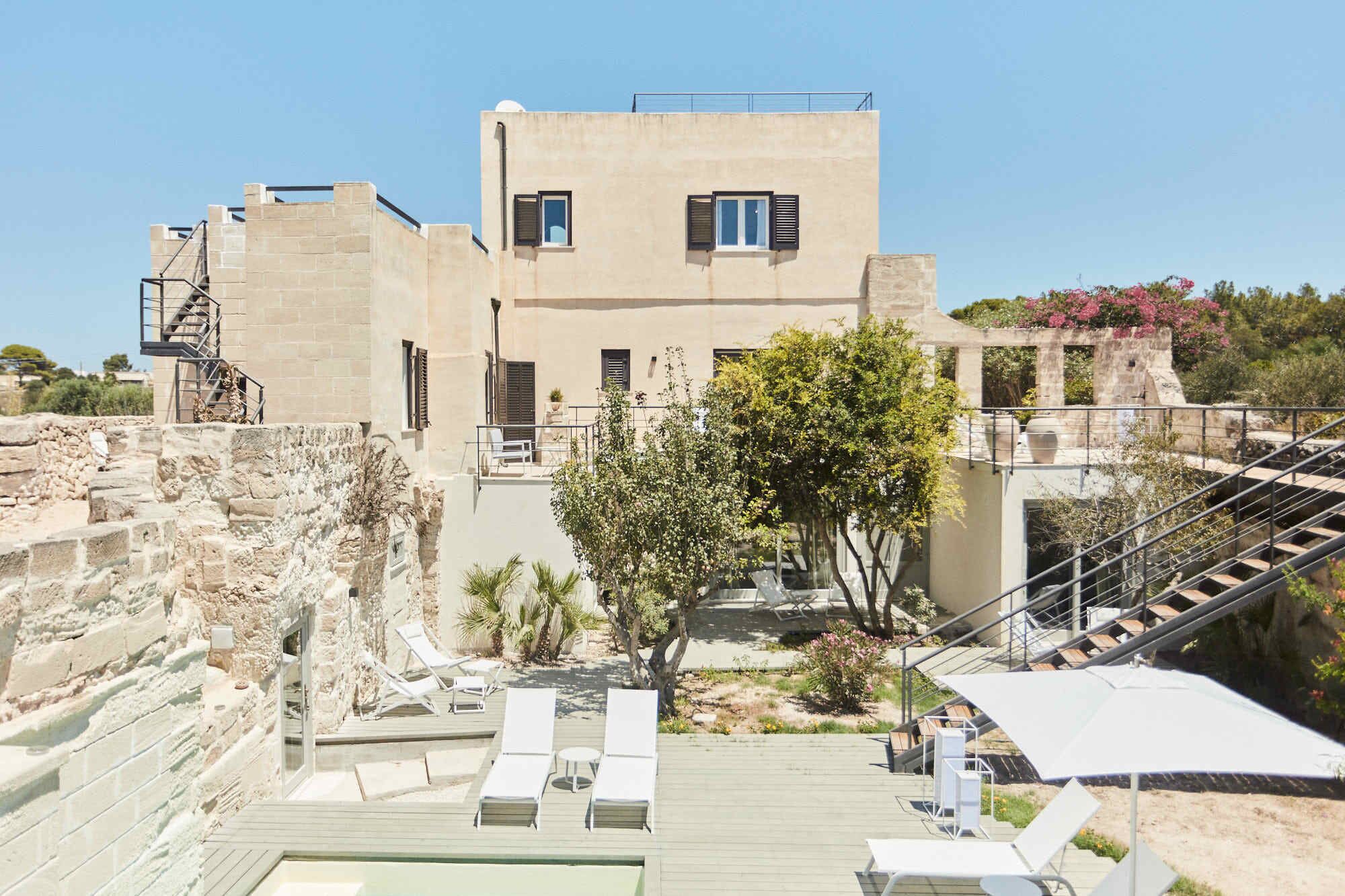 Un bâtiment doté d’une terrasse, d’un espace extérieur aménagé pour s’asseoir et d’un escalier.