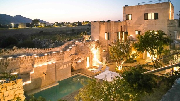 Uma villa moderna com piscina, paredes de pedra e vista para a paisagem circundante.