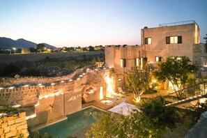 A modern villa with a swimming pool, stone walls, and a view of the surrounding landscape. - Villa Rocce Bianche (Favignana)