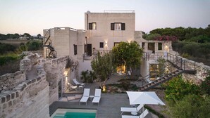 Uma villa moderna com piscina, área de estar ao ar livre e um muro de pedra.