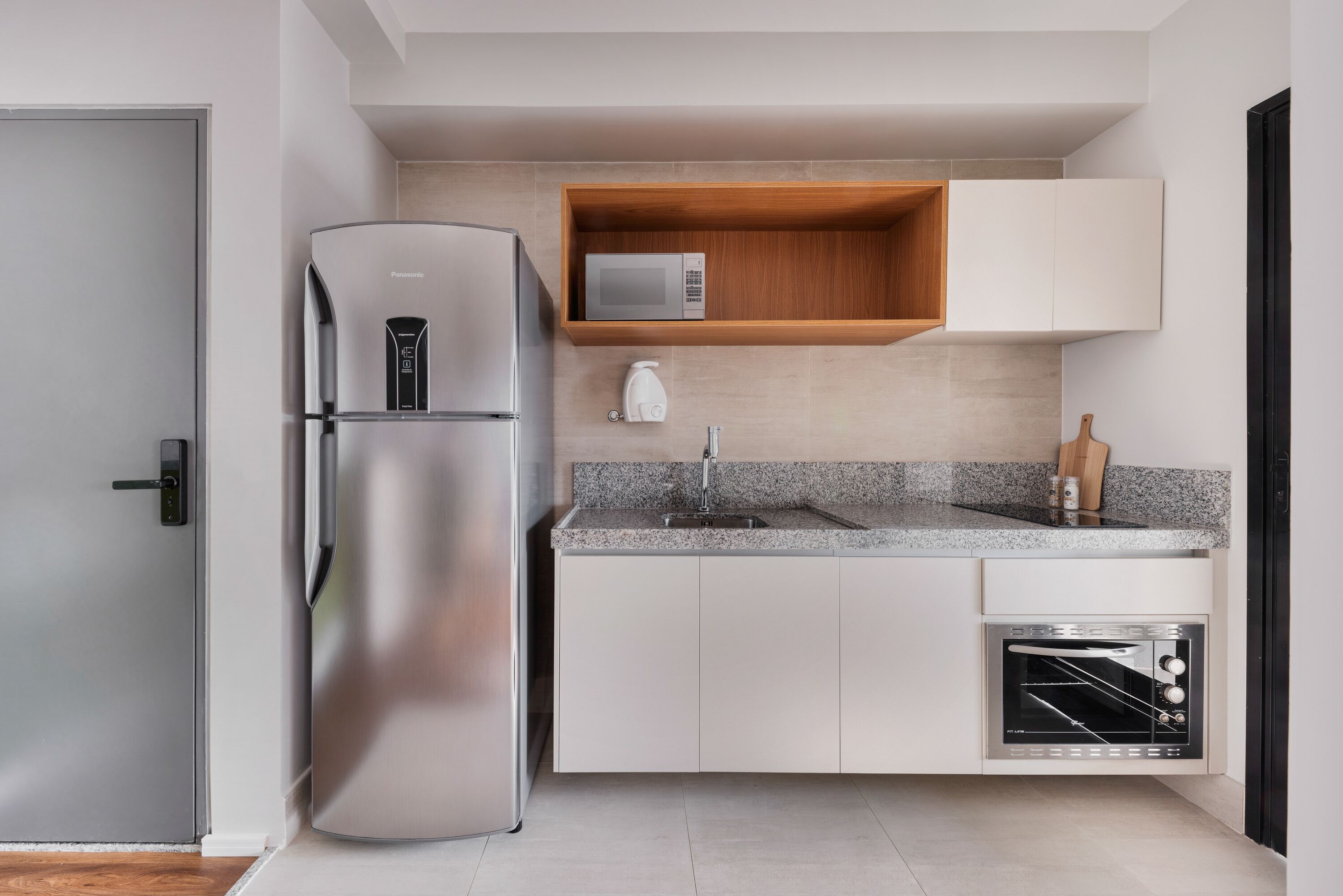 A modern kitchen with a stainless steel refrigerator, built-in microwave, and oven.