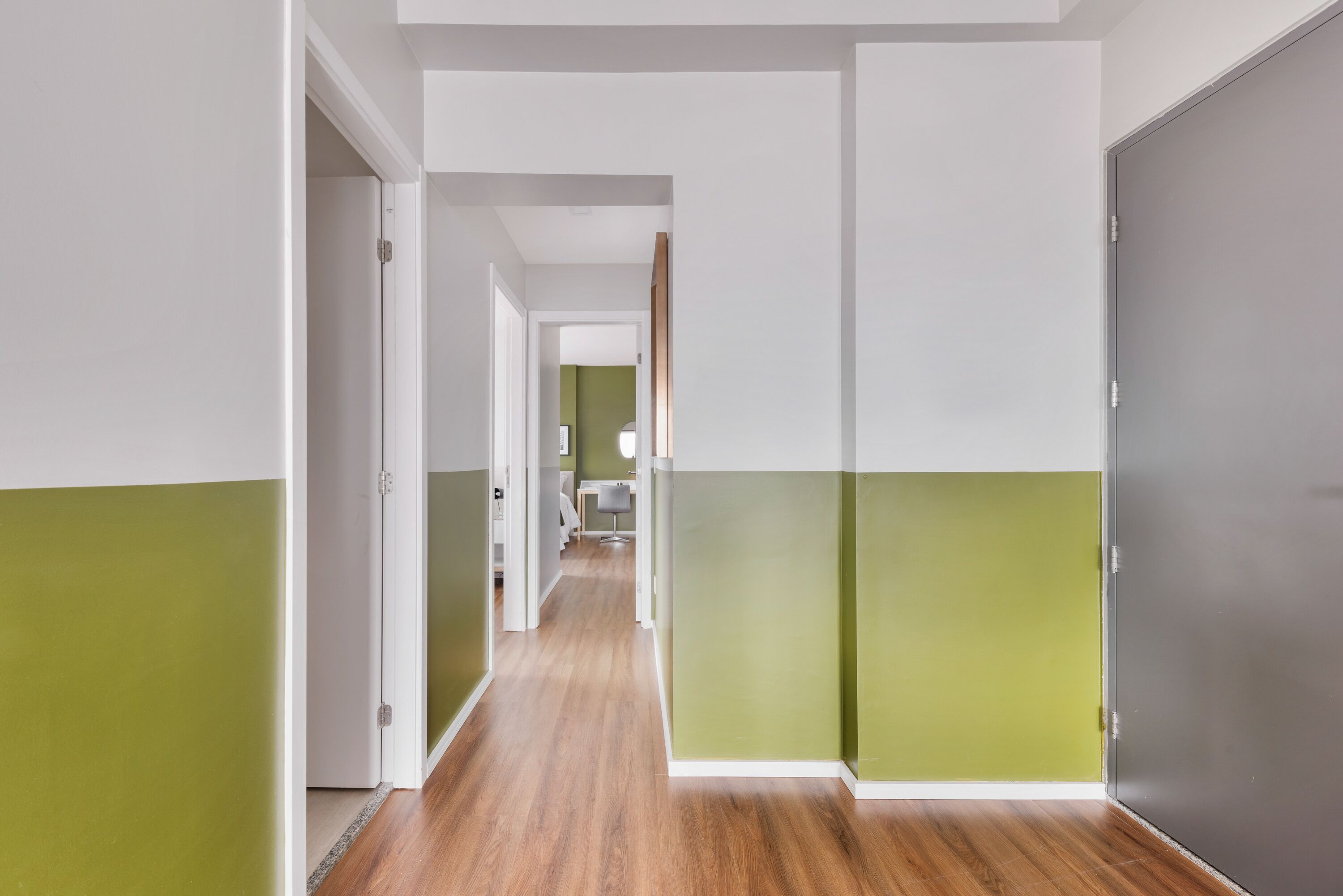 A hallway with a wooden floor and walls painted in green and white.