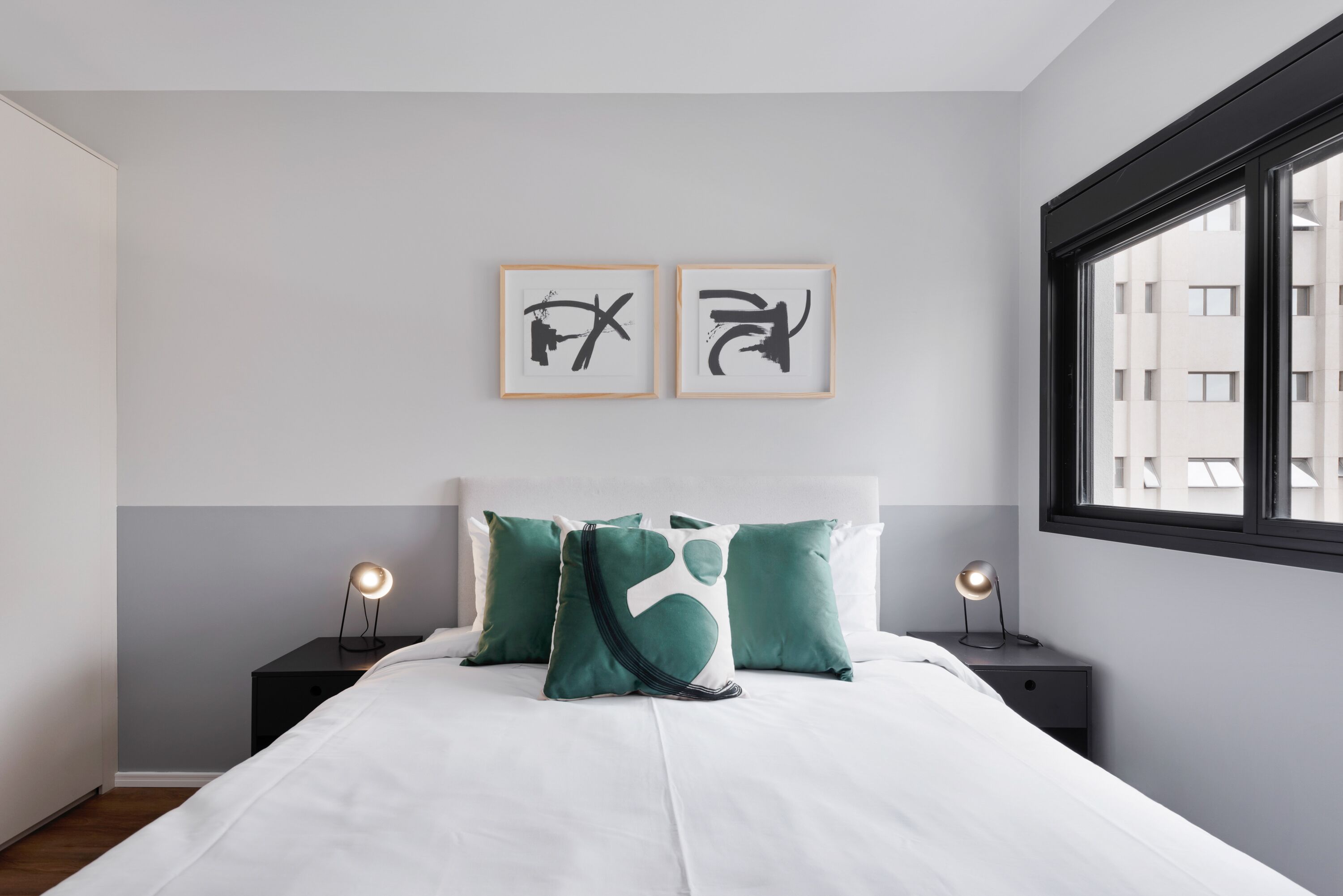A modern bedroom with a bed, two bedside tables, a window, and abstract wall art.