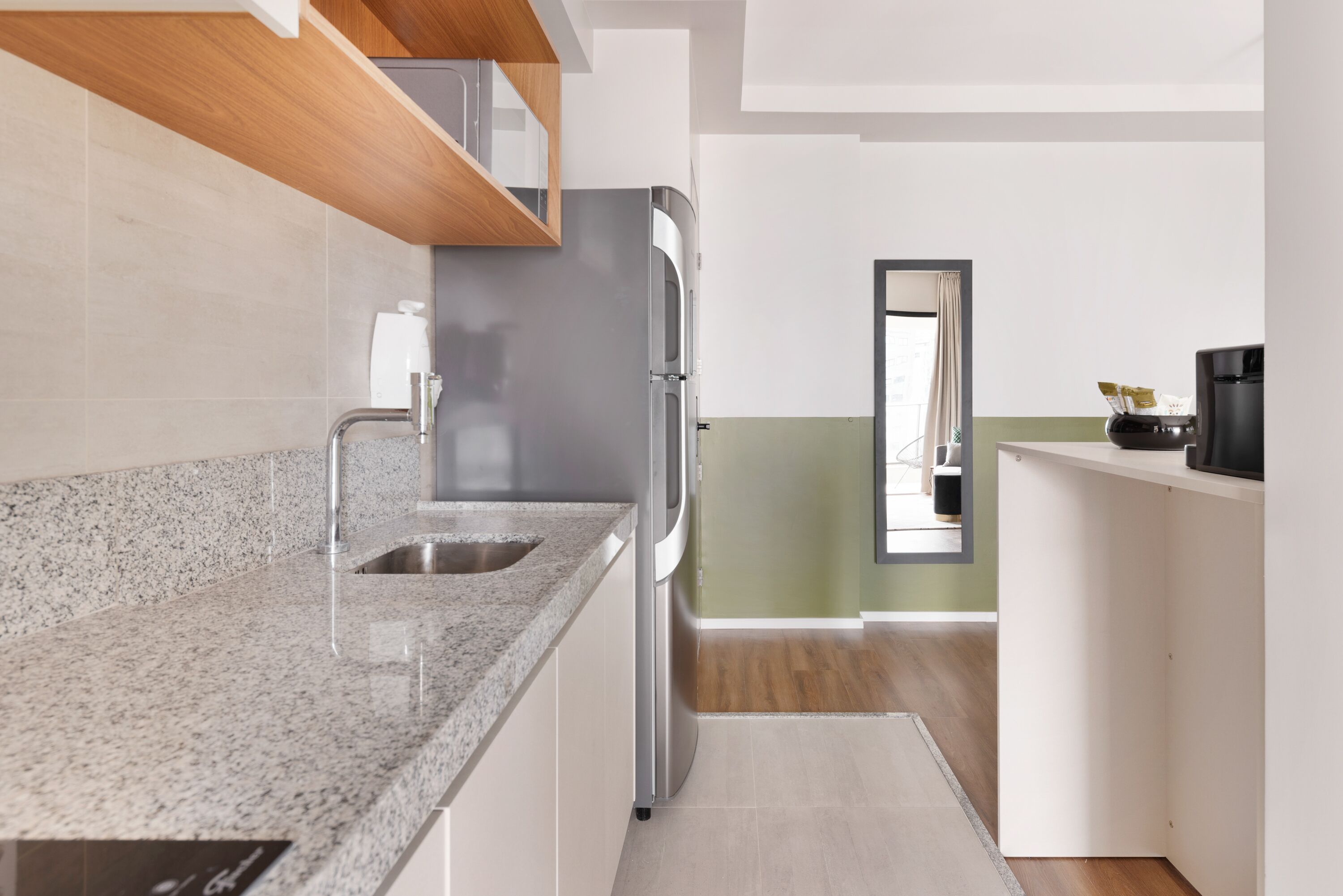 Eine moderne Küche mit Granit Arbeitsplatten, Edelstahlgeräten und einer Holzzielung.