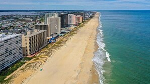 Paisagem costeira com edifícios altos ao longo de uma praia arenosa, com vista para o oceano.