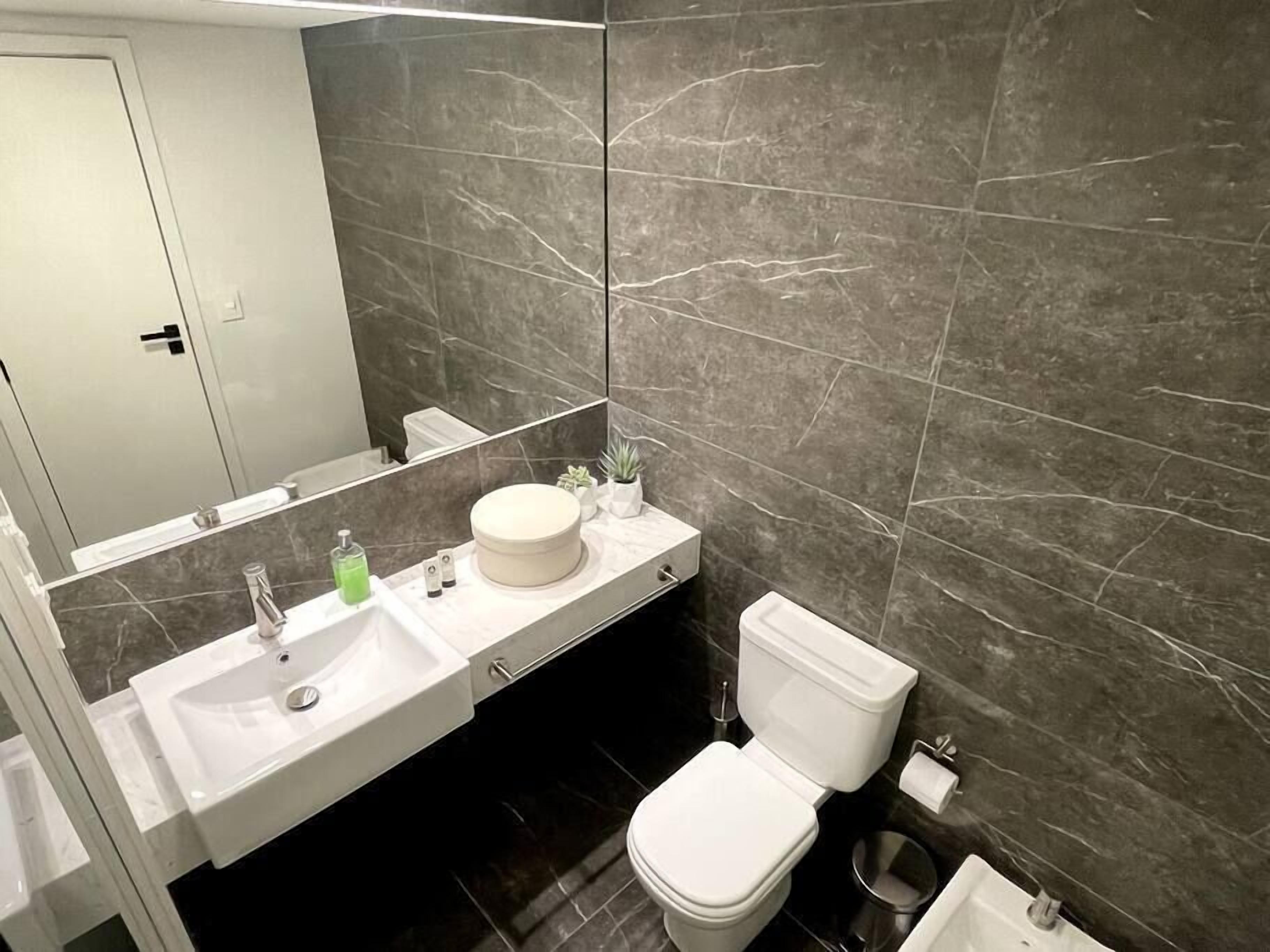 Ein modernes Badezimmer mit einem Doppelwaschtisch, Toilette und einem großen Spiegel.