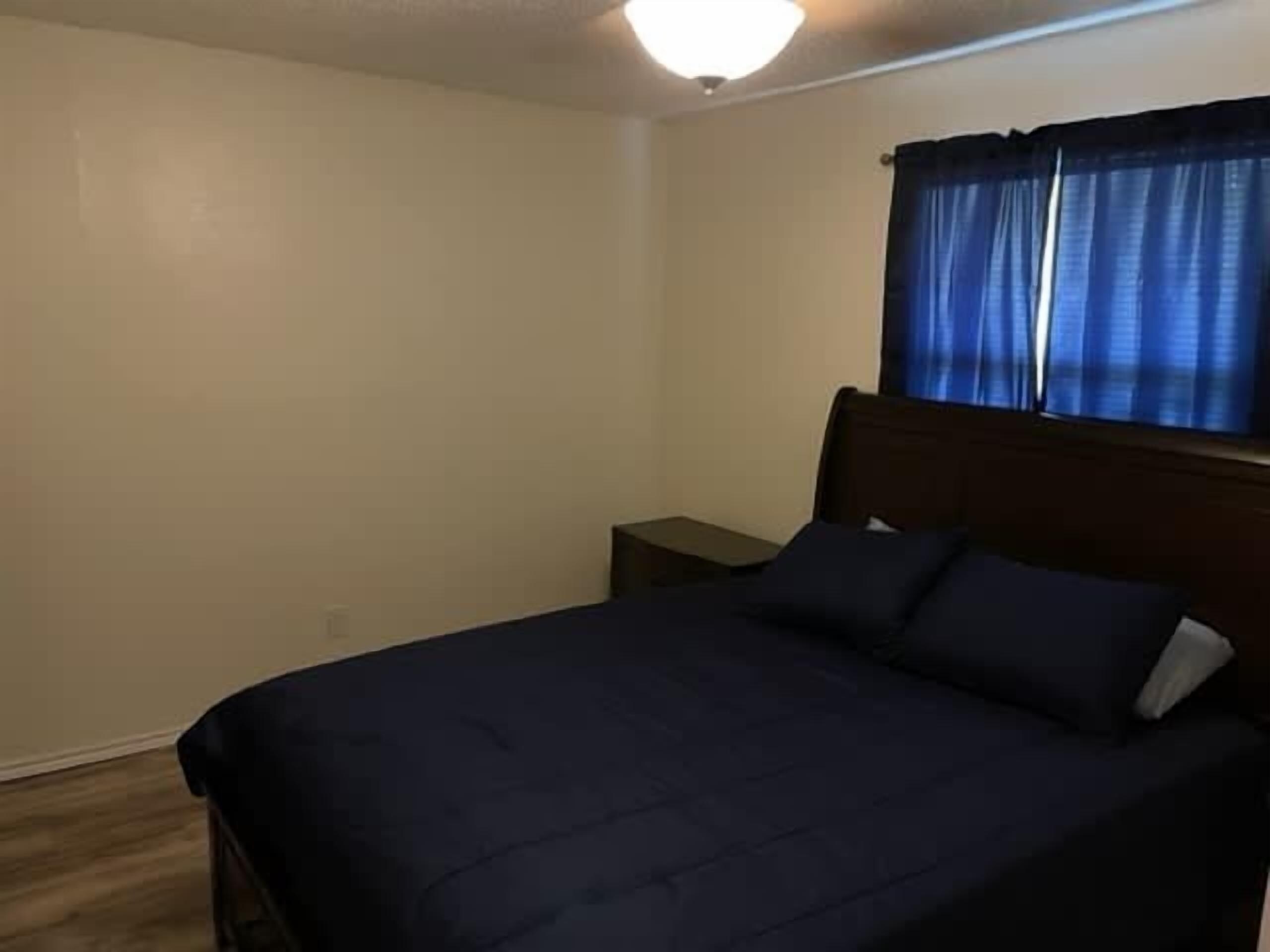 Une chambre à coucher avec un lit, une table de chevet et une fenêtre avec des rideaux.
