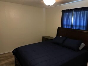 Une chambre à coucher avec un lit, une table de chevet et une fenêtre avec des rideaux.