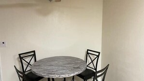 Une table de salle à manger ronde, surmontée d’un plateau en marbre, entourée de quatre chaises noires au design original.
