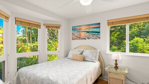 A bedroom with a large bed, a nightstand, and a painting of a beach scene.