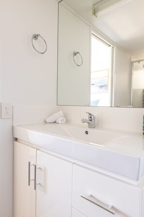 Une salle de bain blanche avec un lavabo, un miroir et une serviette posée sur le comptoir.