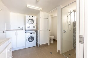 Een kleine badkamer met een wasmachine, toilet en douchecabine.