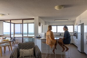 Une cuisine moderne dotée de grandes fenêtres, un coin repas avec vue et un salon comprenant un canapé et une table basse.