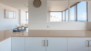Una cocina moderna con un ventanal grande, un reloj en la pared y vistas a la ciudad.
