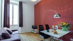 Un salon moderne avec un canapé, une table à manger et des chaises, un téléviseur et un vase de fleurs.