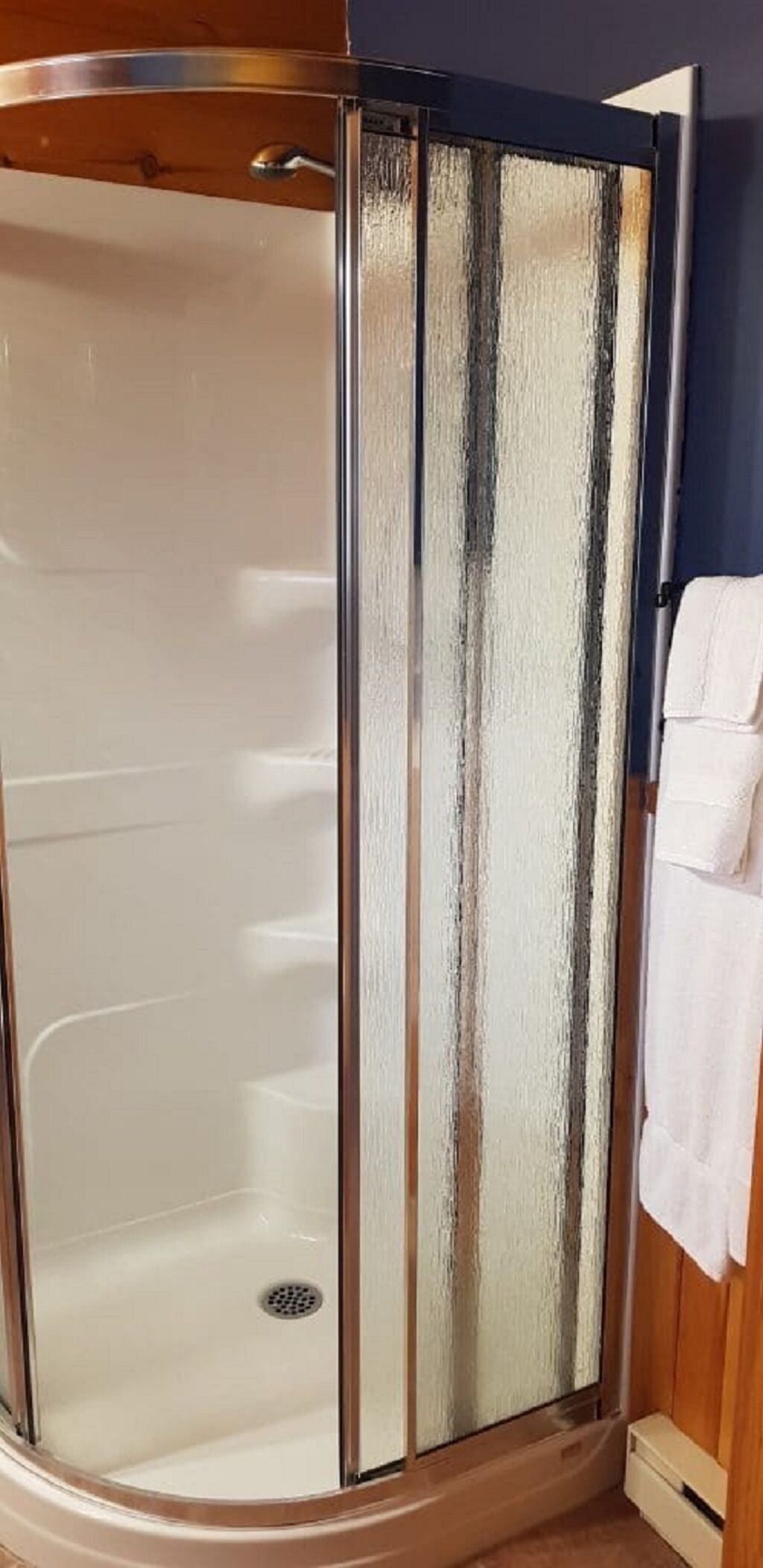 Douchecabine met een glazen deur en houten frame.