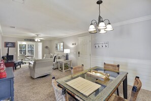 Ein Wohnzimmer mit einem Glastisch, einer Couch und einem Deckenventilator.