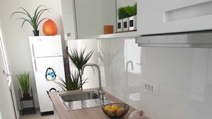 Eine moderne Küche mit einem schwarzen Induktionskochfeld, einer Edelstahl-Spüle und einer Holz Arbeitsplatte.