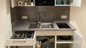Cocina compacta con microondas, lavamanos y almacenamiento integrado.