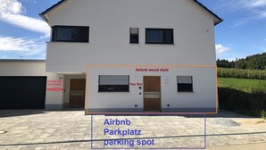 Una casa blanca de dos pisos con garaje, identificada como un Airbnb de estilo rústico.
