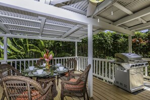 A covered outdoor patio with wicker furniture, a grill, and a table set for dining. - Haena Place, Walk to Beach Tropical Home TVNC#4232 (Haena)