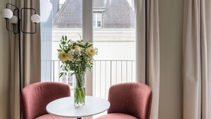 A room with two pink chairs, a small white table, and a vase with flowers. - Numa Zurich Craft (Zürich)