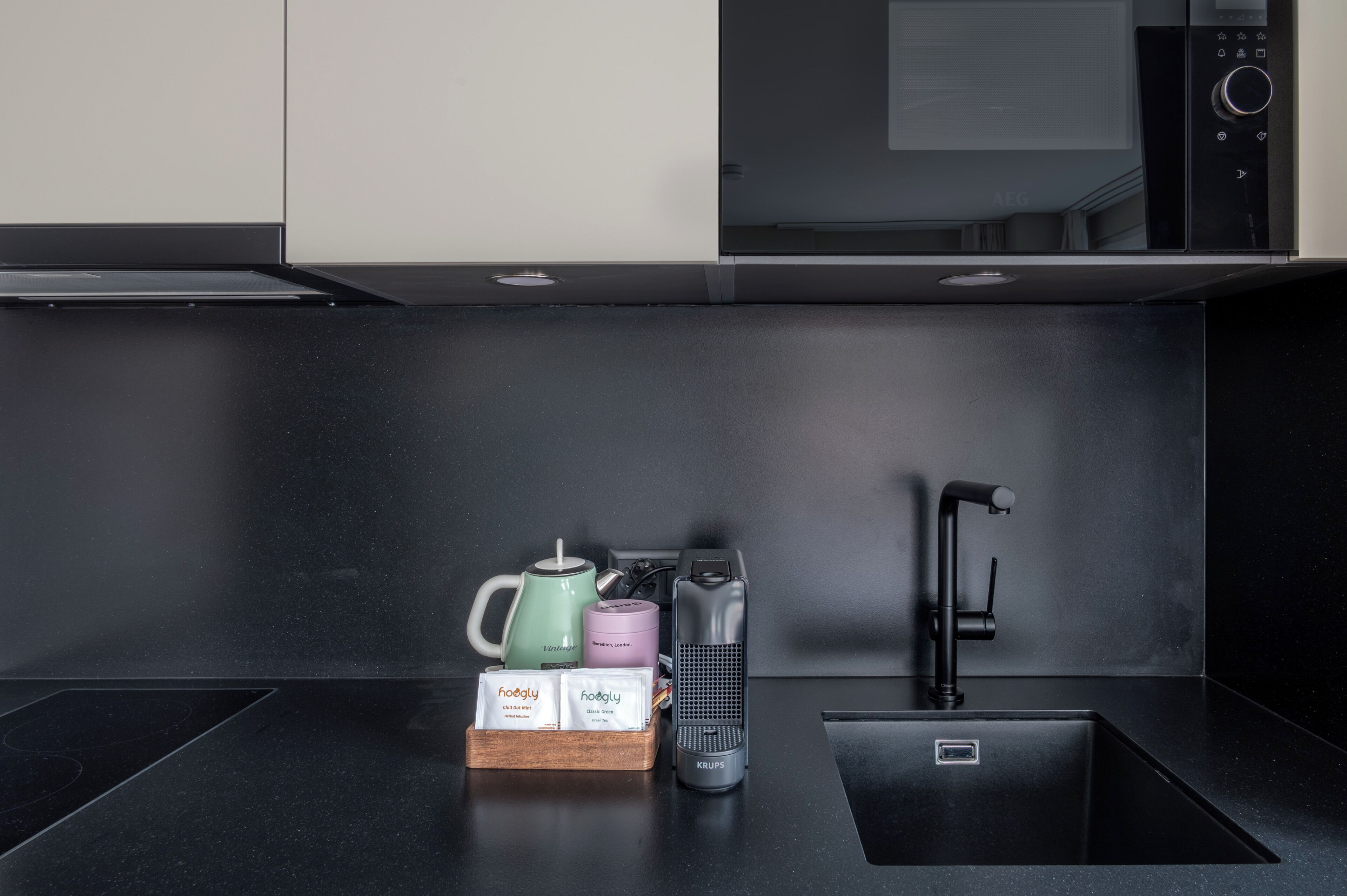 Una cucina moderna con un piano di lavoro nero, una macchina per il caffè, un bollitore, un tostapane e un lavello.