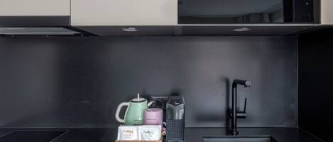 Una cucina moderna con un piano di lavoro nero, una macchina per il caffè, un bollitore, un tostapane e un lavello.