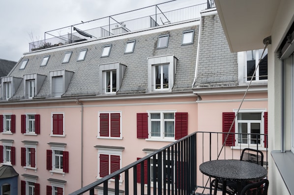 Un immeuble d’habitation doté d’un balcon, de volets rouges et d’un toit gris.