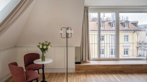 A modern room with a large window, a floor lamp, a small table with a vase, and a red chair. - Numa Zurich Craft (Zürich)