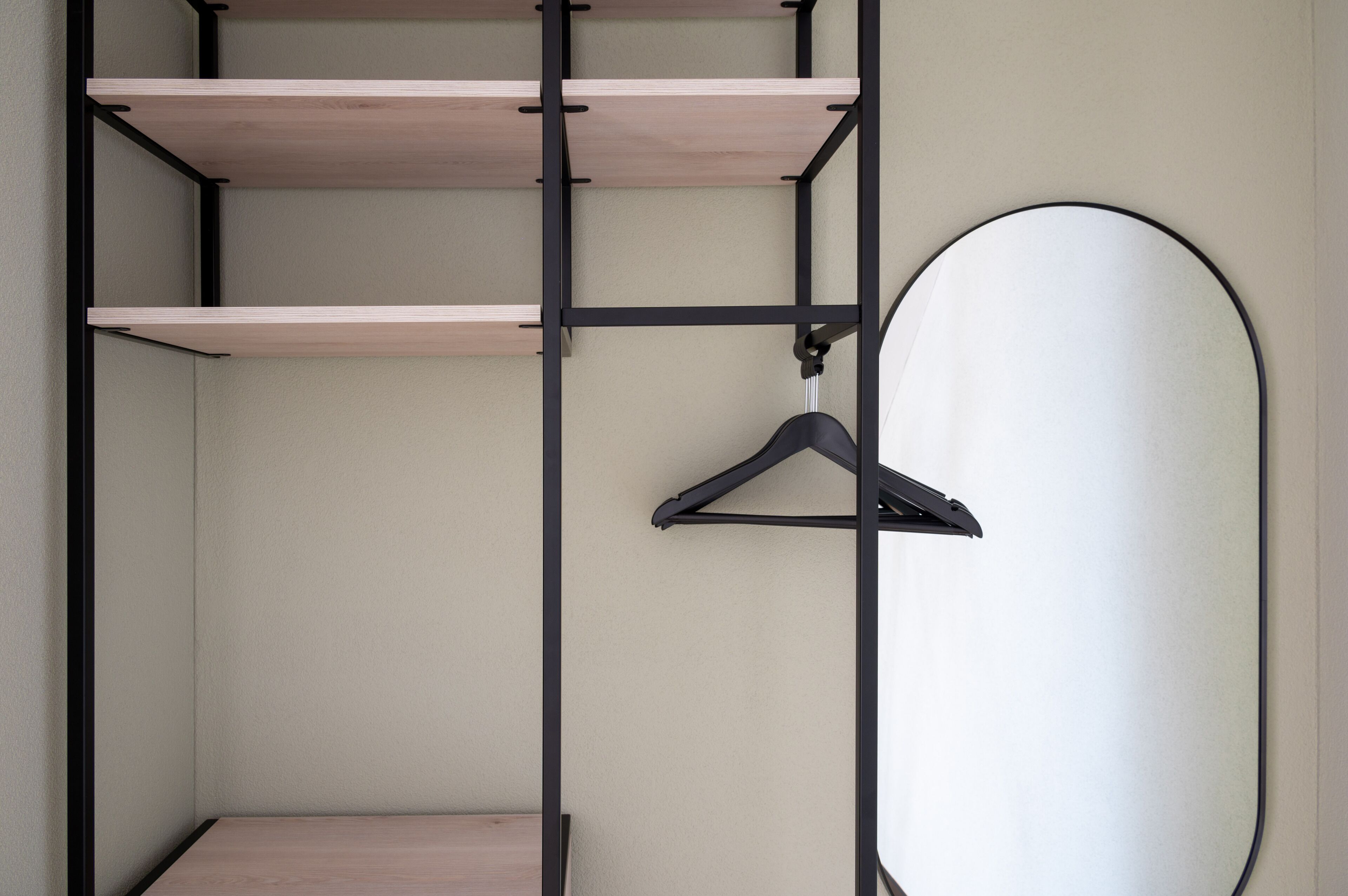 Une pièce au décor minimaliste, avec une étagère en bois et un miroir rond.