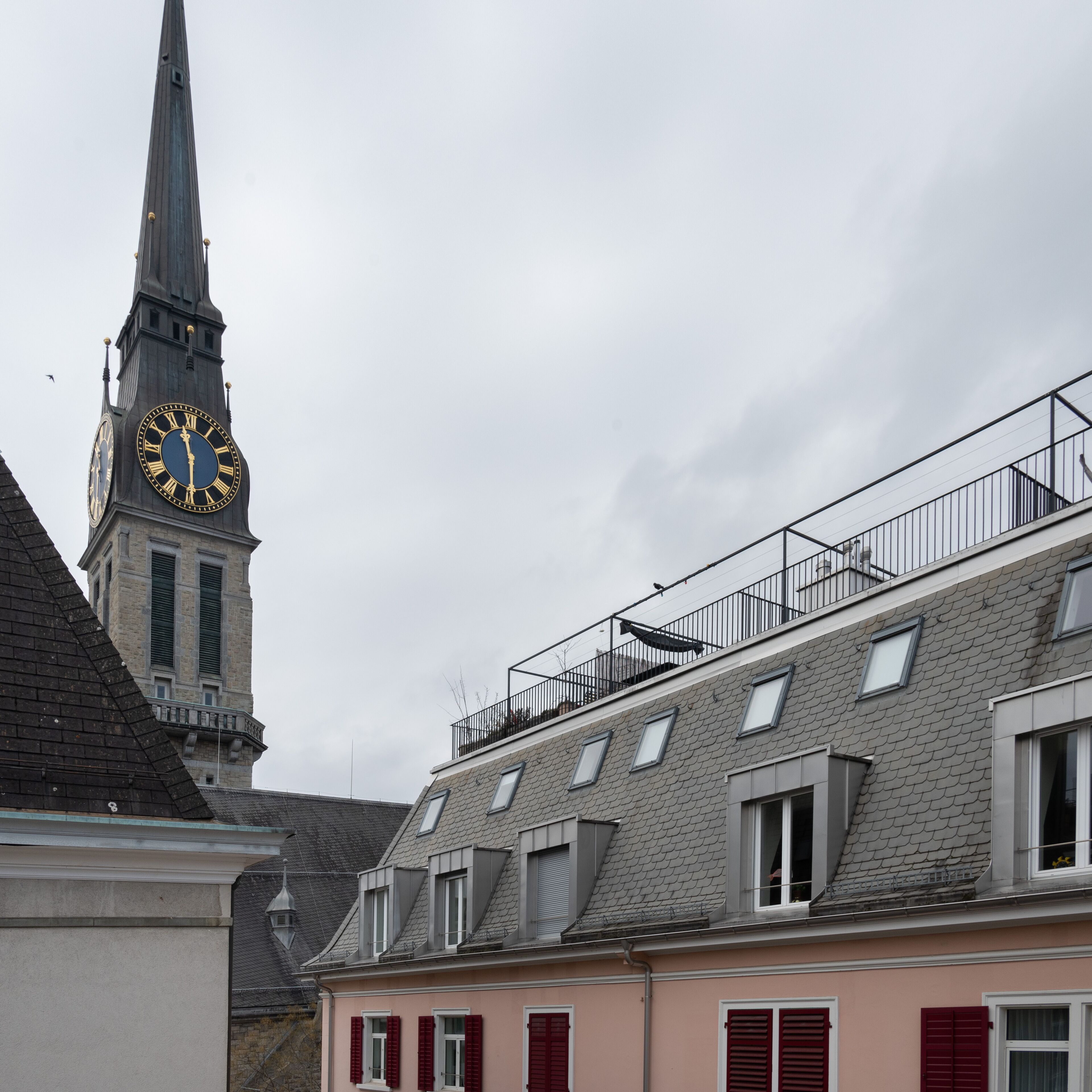 Ein Gebäude mit einem Glockenturm, roten Fensterläden und einem Balkon.