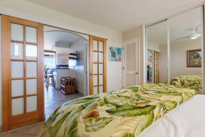 A hotel room with a bed, a sliding door, a kitchenette, and a dining area.
