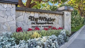 Un muro de piedra con un letrero que dice 'The Whaler On Kaanapali Beach' y un aviso de propiedad privada.
