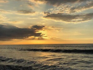 Atardecer sobre el océano con olas en primer plano.