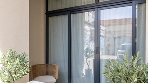 A balcony with a wicker chair, a white sofa, and two potted plants. - Florella Residences 3 pièces Marceau (Cannes)