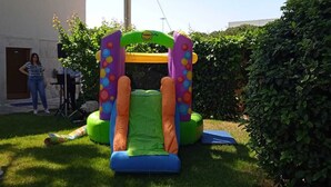 An inflatable bounce house in a backyard with a white building in the background. - BB Delle Murge (Corato)