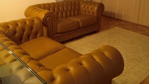 A living room with a brown sofa, a glass coffee table, and a patterned rug. - BB Delle Murge (Corato)