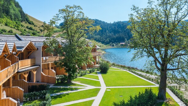 Una cabaña de madera con vistas a un lago y colinas.