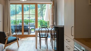 Una cocina moderna con armarios de madera, un área de comedor con mesa y sillas, y un amplio ventanal corredero que da a un patio exterior.