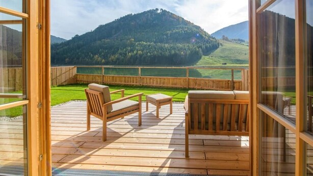An open deck with wooden furniture and a view of a lake and mountains. - Chalet am Schneeberg See (Puchberg Am Schneeberg)
