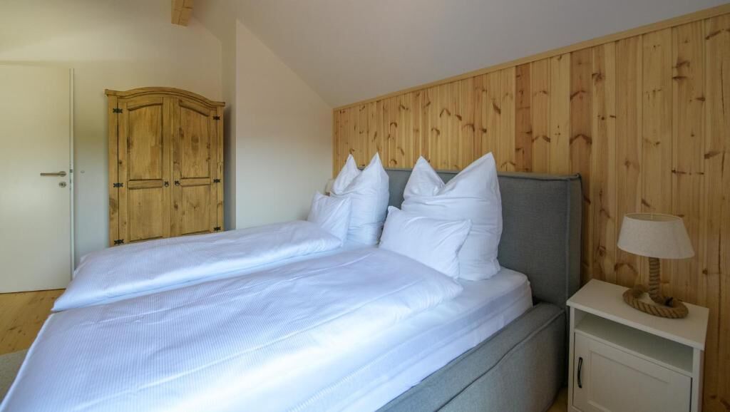 Un dormitorio con cama, armario de madera y mesita de noche con lámpara.