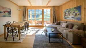 Amplia sala de estar con mesa de comedor de madera, sofá y un ventanal que ofrece vistas al exterior.