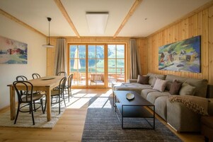 Uma sala de estar ampla com uma mesa de jantar de madeira, sofá e uma grande janela com vista para o exterior.